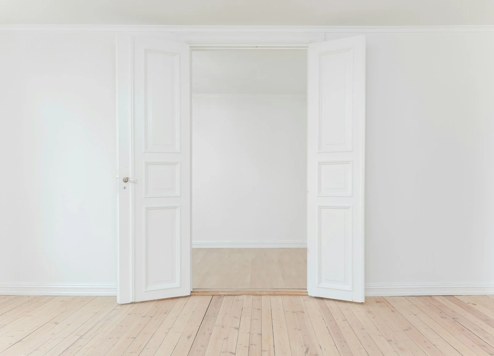 Open white doors leading into a sunlit room